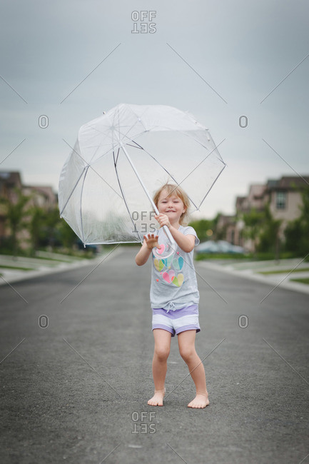A little girl with a clear plastic bubble umbrella smiles