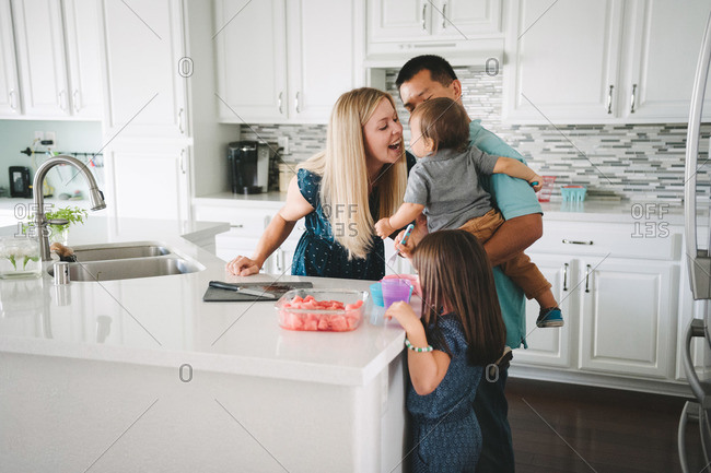 A family gathers in the kitchen for a watermelon snack