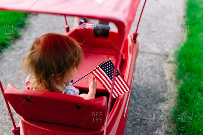 Girl in a red wagon with an American flag
