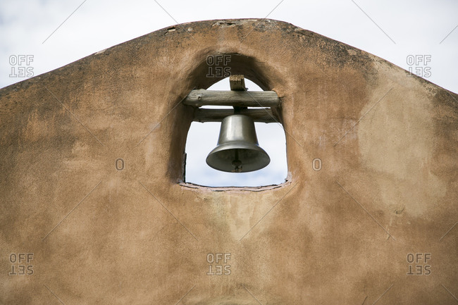 A silver bell atop an adobe building
