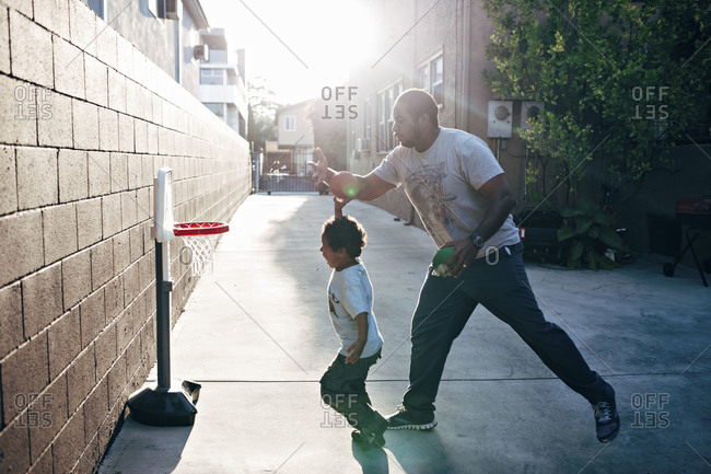 Dad and little boy playing basketball with toy hoop