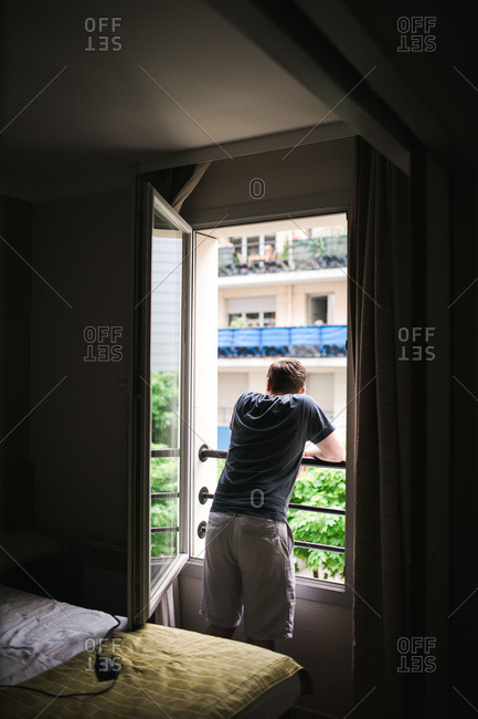 Man staring out Parisian hotel room window