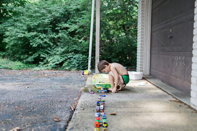 Boy playing in driveway with toy cars in water