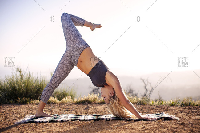 Woman in downward dog yoga pose with one leg raised