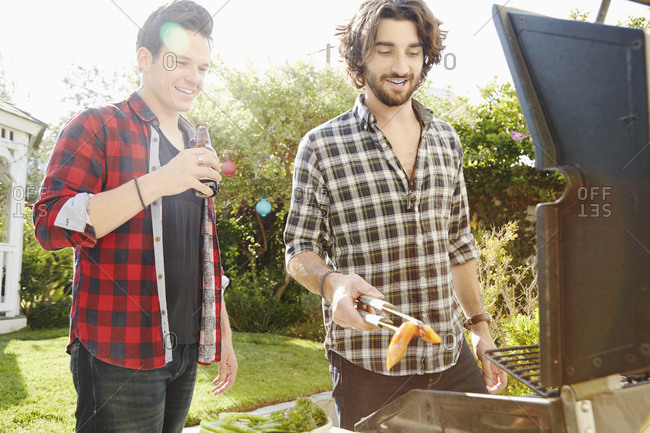 Friends tend the grill at a backyard party