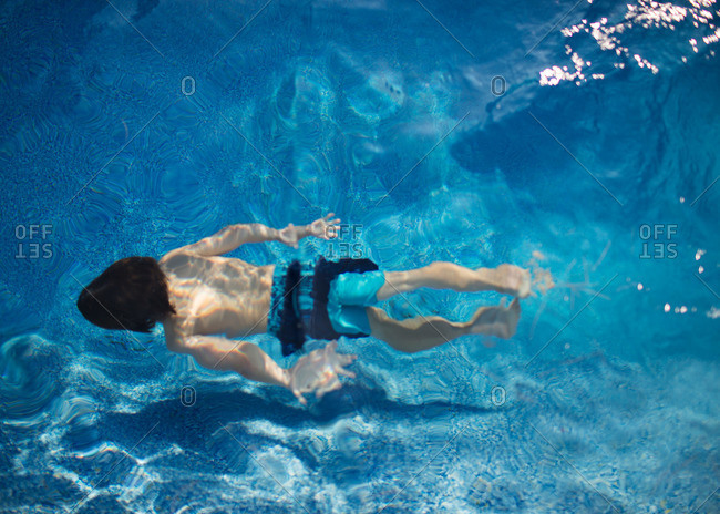 A boy swims underwater in a swimming pool
