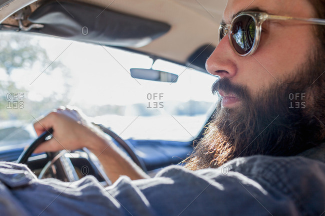 Bearded young man in driver\'s seat of vintage car