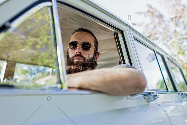 Low angle view of bearded man in driver\'s seat of vintage car