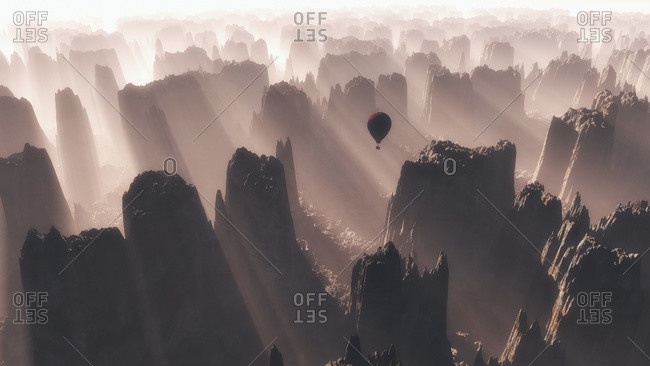 Hot air balloon flying over rough mountain range at sunrise