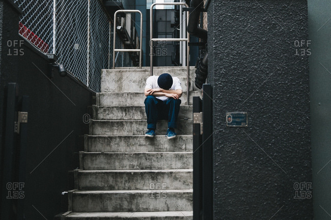 Young man sitting on steps with his head down