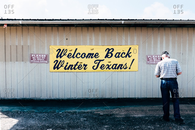 Man standing in front of a welcome sign on a building in Texas