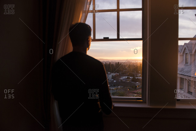 Man looking out a window at the sunset in Berkeley, California