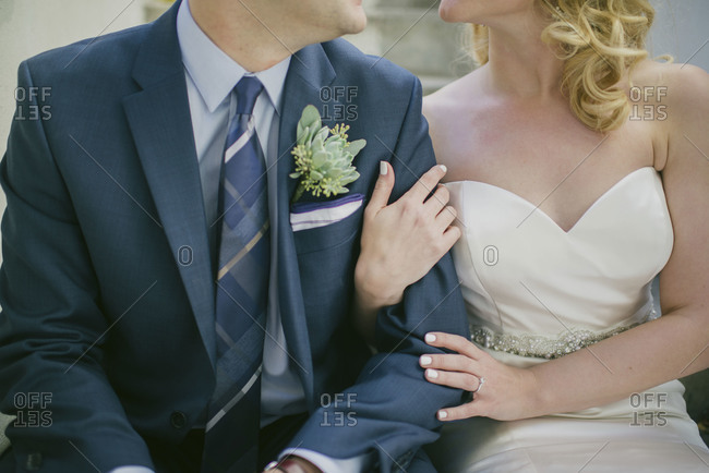 Seated portrait of groom and bride from neck down