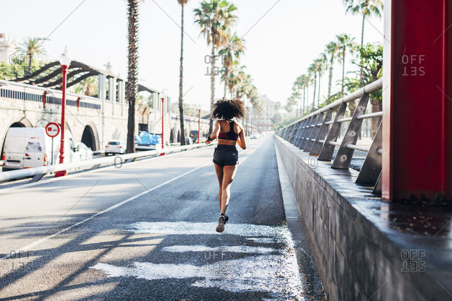 Back view of jogging young woman on a street