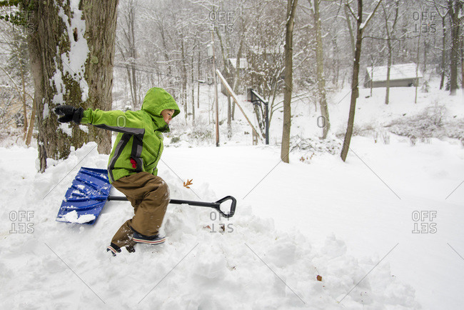 Young boy with snow shovel in deep snow