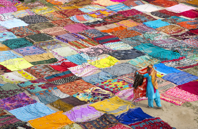 Person laying out washed saris in field