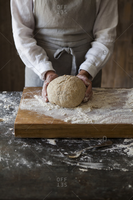 Womans hands kneading and shaping bread dough on floured board