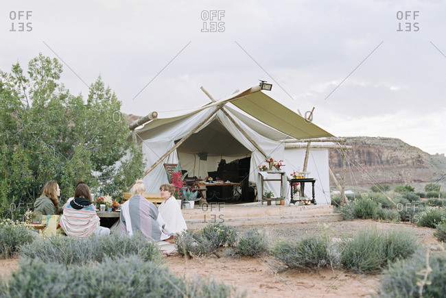 Group of women enjoying an outdoor meal in a desert by a large tent