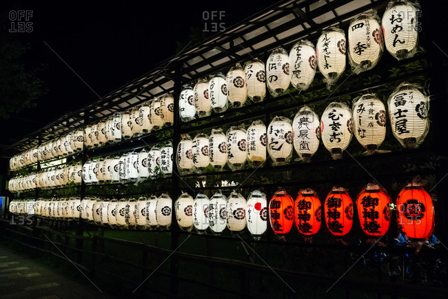 Rows of white lanterns at night with five red ones in the lower right corner