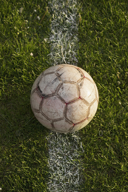 Close-up of soccer ball on white line on soccer pitch