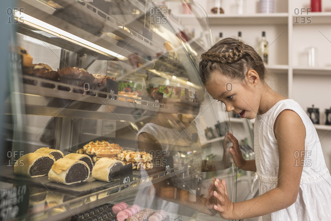 Side view of girl admiring dessert in bakery shop