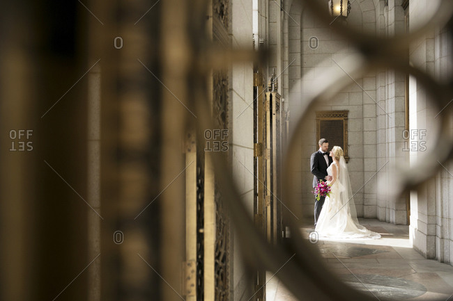 A bride and groom stand  in the entrance to a hotel