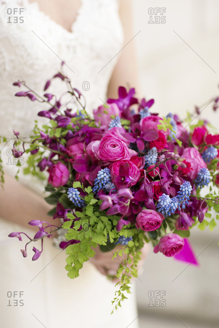 A bride holds her bouquet of bright purple flowers