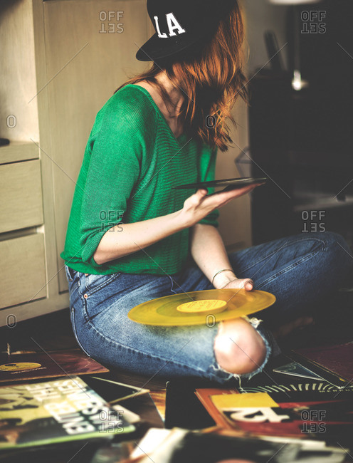 Young woman sitting on the floor holding a vinyl album
