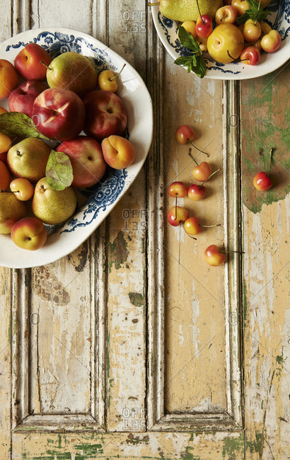 Platters of fresh summer fruits on vintage painted paneled surface