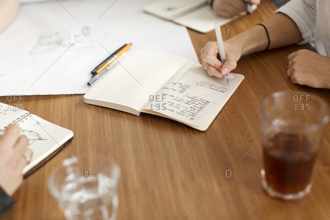 Four people taking notes and drawing during meeting