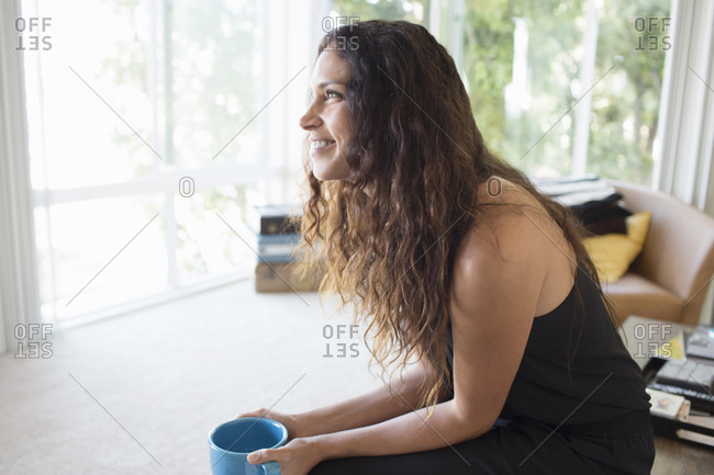Side view of a woman holding a mug in a naturally lit living room