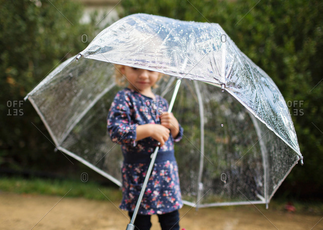 Little girl standing under a clear umbrella