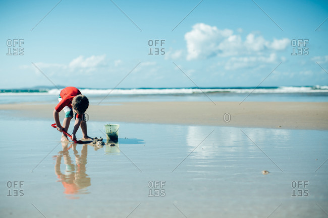 Little boy on the beach with a pail and shovel