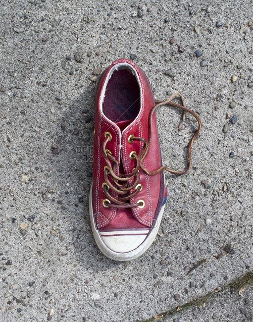 Single red sneaker on a sidewalk