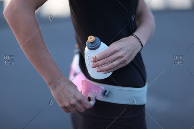 Woman attaching water bottle to running belt