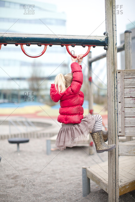 Little girl hanging on climbing pole