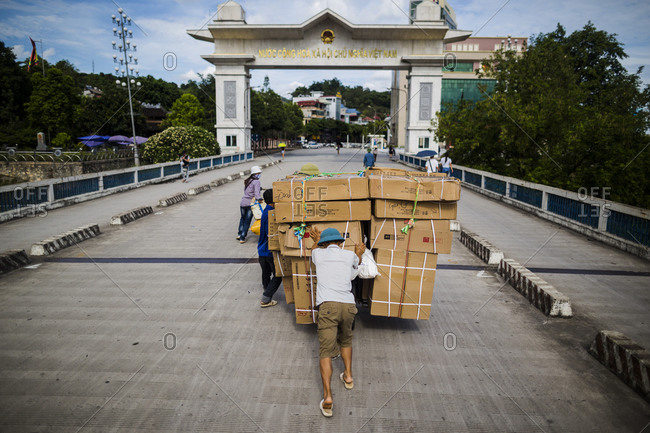 Vietnamese workers push a cart loaded with goods across the pedestrian crossing back into Lao Cai, Vietnam, from across the border in Hekou, China