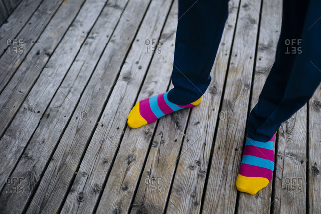 A groom wears colorful socks on a wooden deck in Nova Scotia, Canada