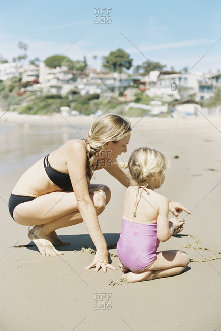 Woman in a bikini playing with her daughter on a sandy beach