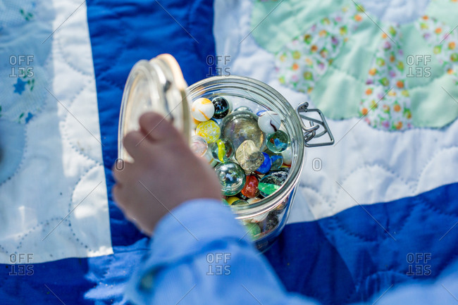 Child\'s hand opening a jar of marbles