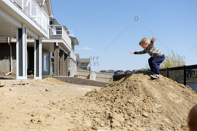 Little boy playing on dirt pile in backyard