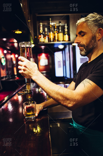 Waiter pouring whiskey in an Irish pub