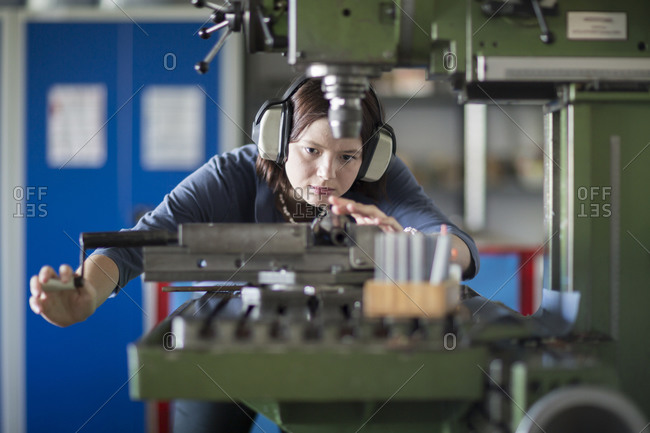 Young woman with ear protectors working at machine