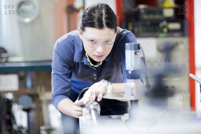 Young woman with safety goggles working at machine