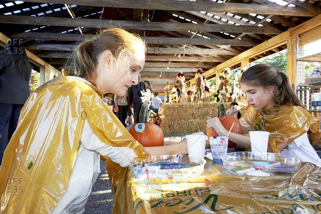 Girls painting pumpkins at a fall festival