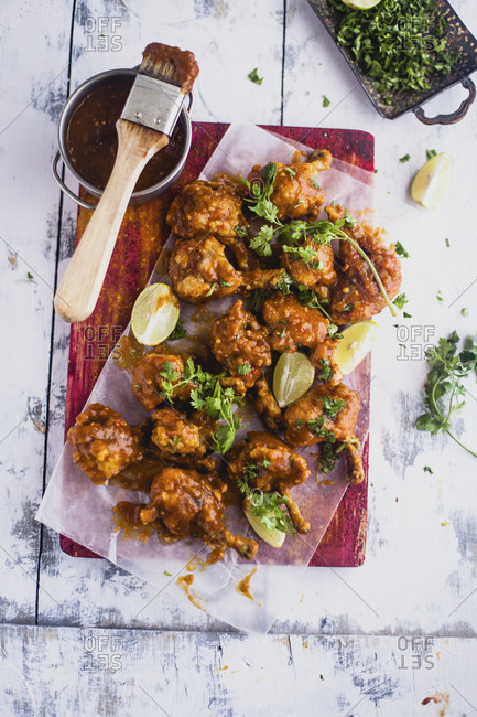 Mango chili chicken lollipops with a bowl of sauce