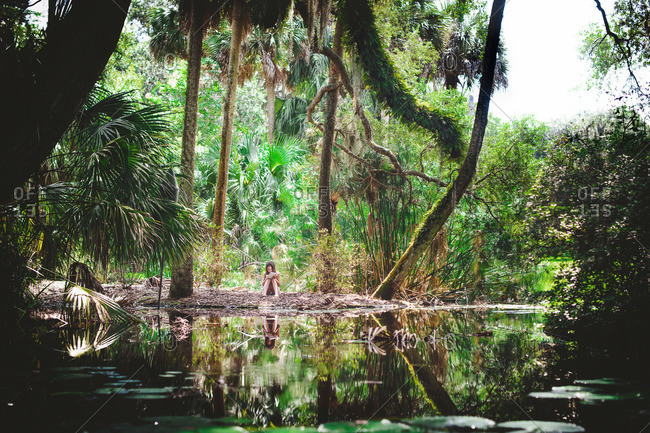 A girl writes in a notebook by a swamp
