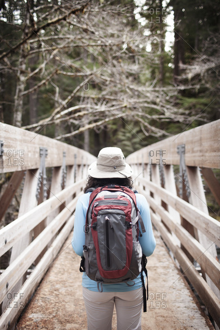 A woman with backpack on a forest bridge