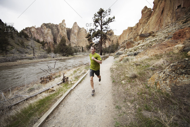 Man jogging along river trail in wilderness