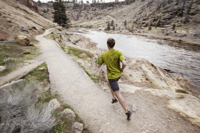 Man jogging on river trail in wilderness